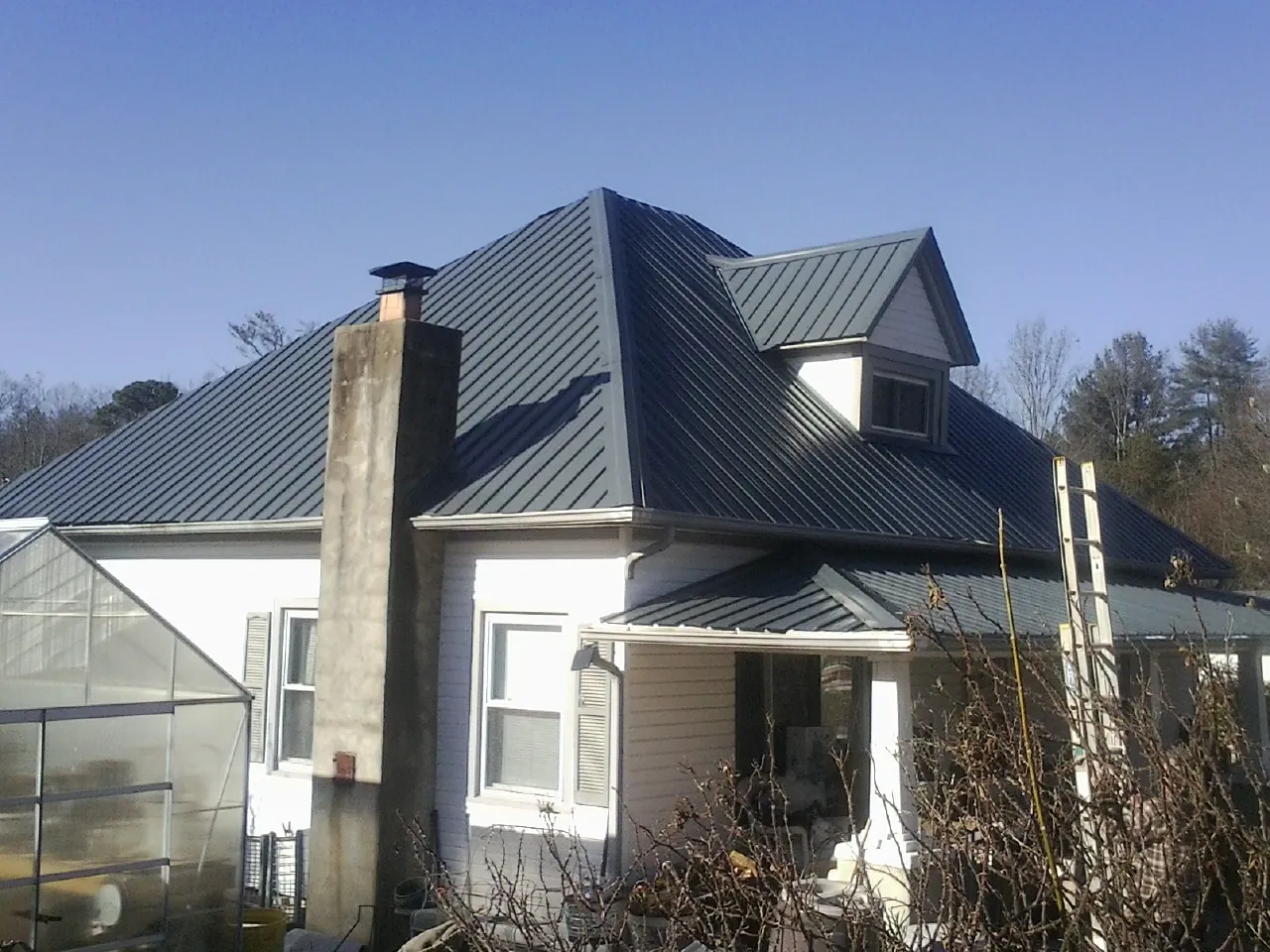 Dark blue standing seam metal roof on a white farmhouse with dormer — Slate & Tile Roof Repair by Roofing Brothers in Bound Brook