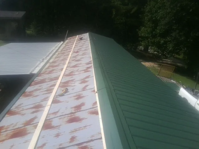 Old rusted panels beside newly installed green metal roofing — Wind Damage Roof Repair by Roofing Brothers in Bound Brook