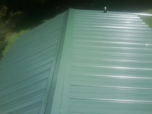 New green metal panels meeting at the ridge of a roof — Flat Roof Repair work by our crew in Bound Brook