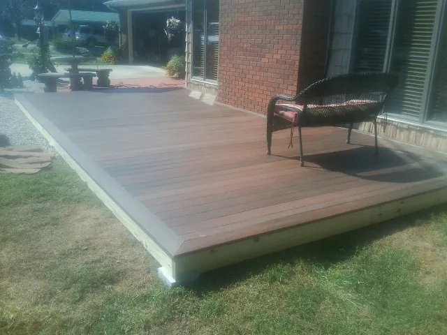 New wood deck and wicker chair beside a brick house in Bound Brook