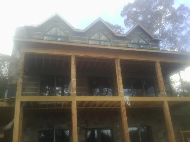 Dormers and porch framing on a large log home under construction — Roof Coating work by our crew in Bound Brook