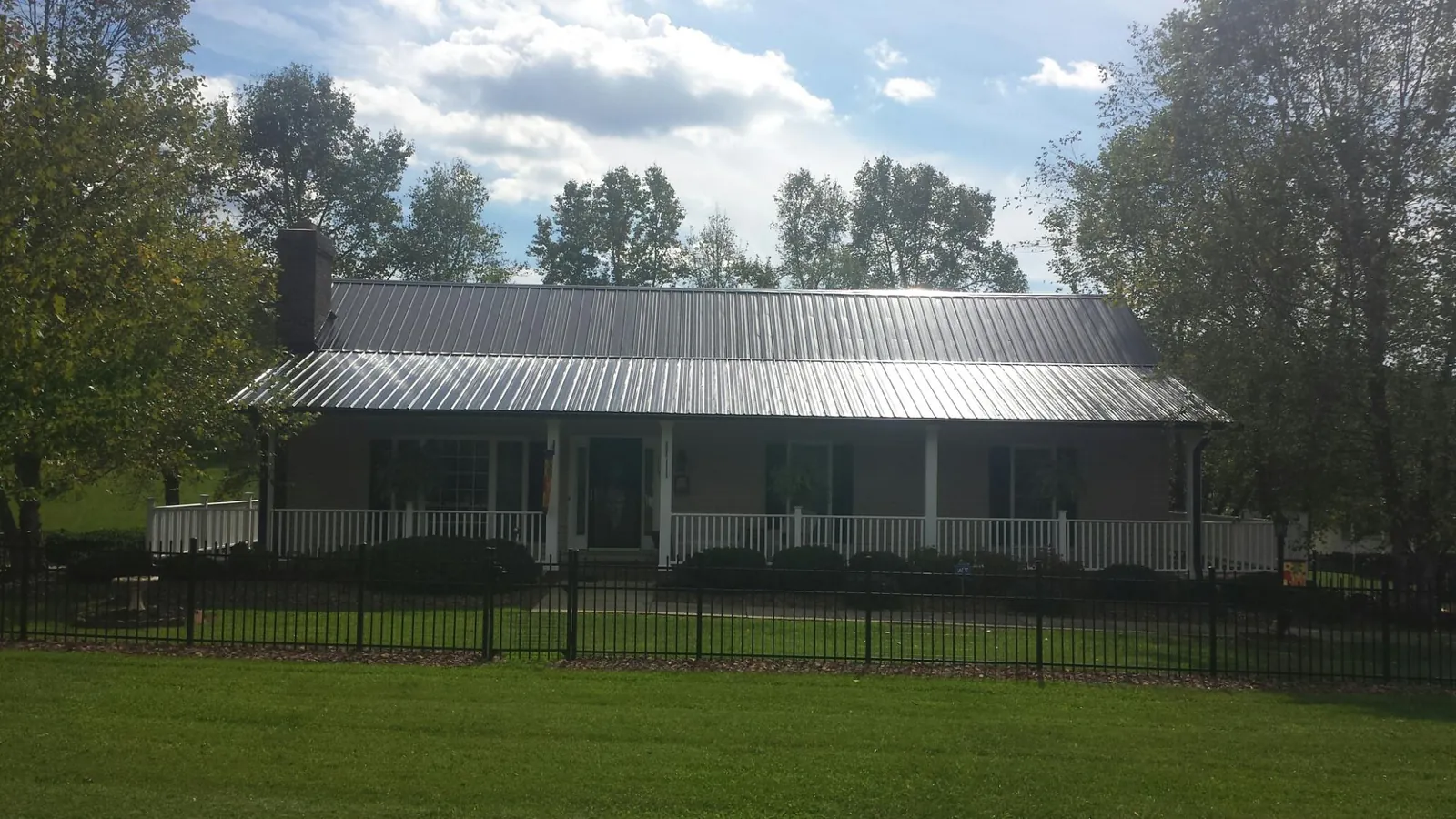 Gray metal roof on a brick ranch with a full width front porch — Gutter Guard Installation work by our crew in Bound Brook