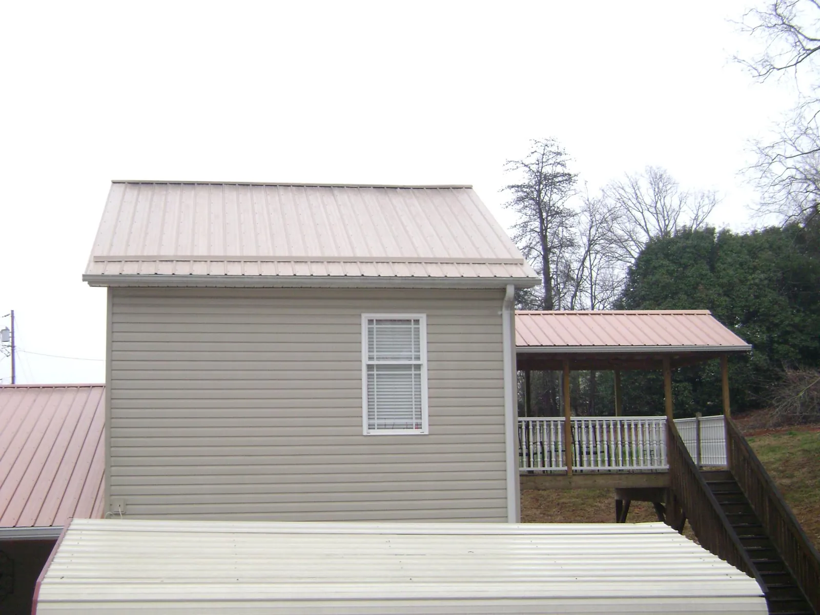 Tan metal roofs on a two story addition and attached porch, from a Roof Replacement job in Bound Brook