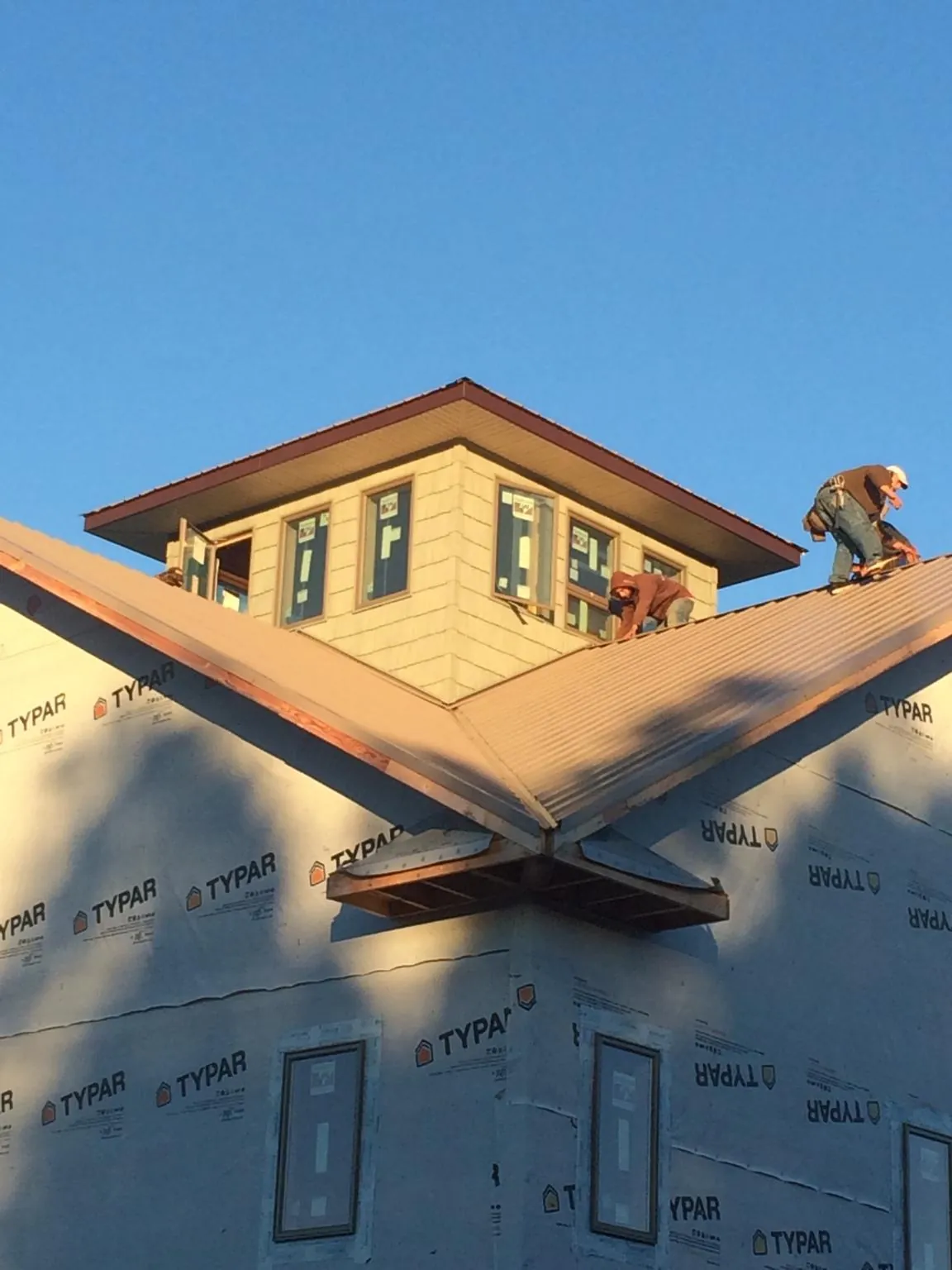 Roofers working around a rooftop cupola on a new metal roof at sunset — Roof Waterproofing in Bound Brook by Roofing Brothers